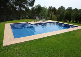 Piscina adaptada al terreno con escalera gresite azul