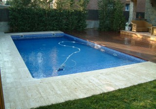 Piscina de gresite azul con travertino y tarima