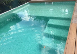 Piscina con escalera y solarium en gresite verde