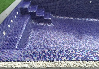 Piscina con revestimiento nacarado azul, banco y escalera