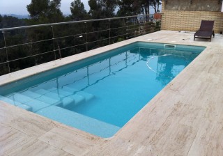 Piscina con revestimiento turquesa con brillos y travertino