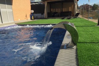 Piscina con carpa y césped artificial